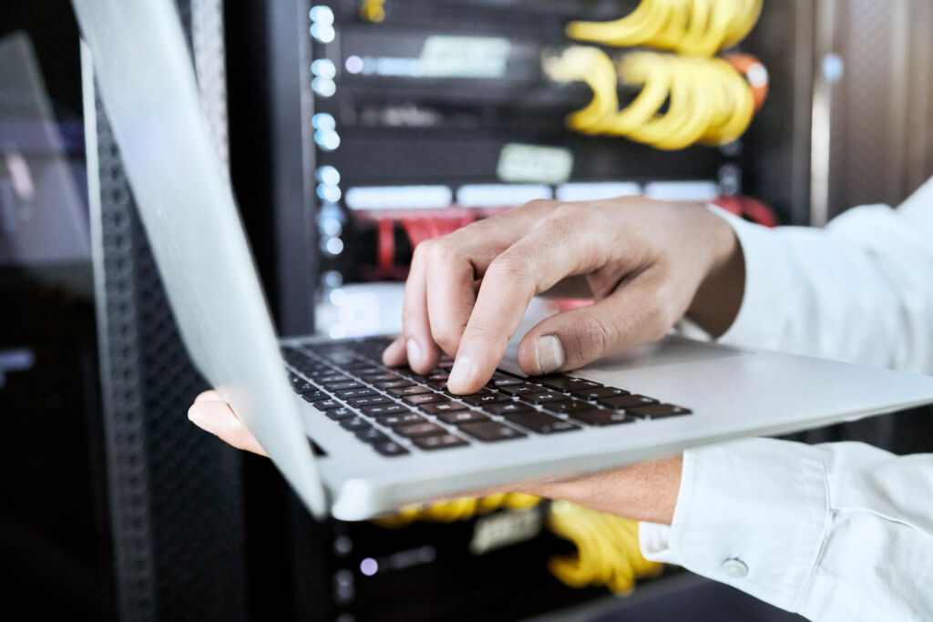 A person using a laptop to monitor fraudulent traffic patterns, illustrating monitoring and detection strategies for toll fraud